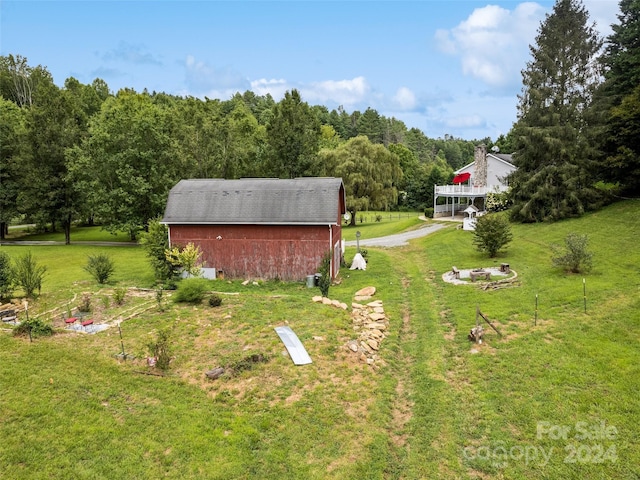 view of yard featuring a barn, a view of trees, and an outbuilding