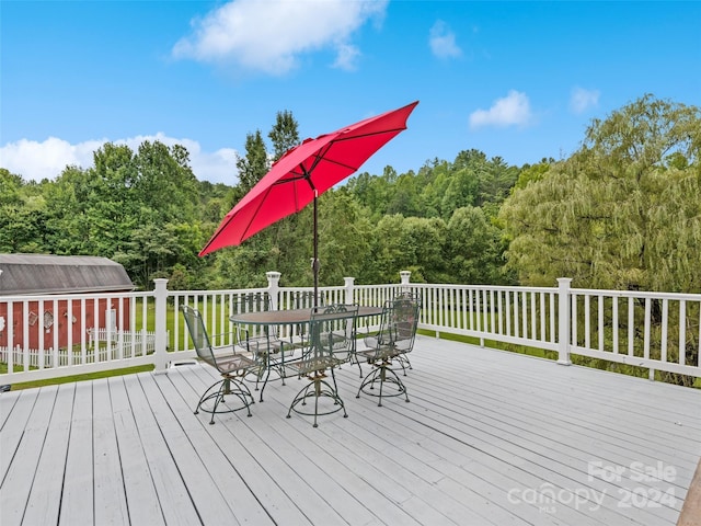 deck with outdoor dining space and a view of trees