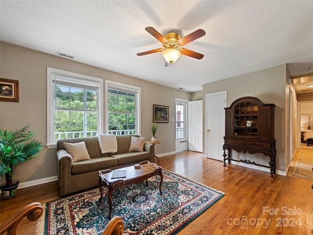 living area featuring a wealth of natural light, a textured ceiling, wood finished floors, and ceiling fan