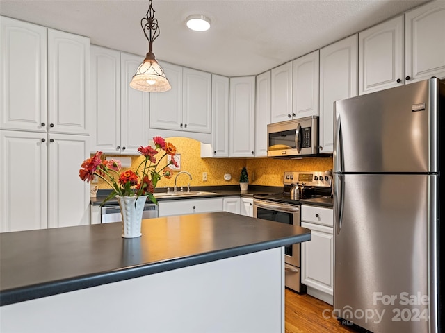 kitchen with stainless steel appliances, white cabinets, a sink, and dark countertops