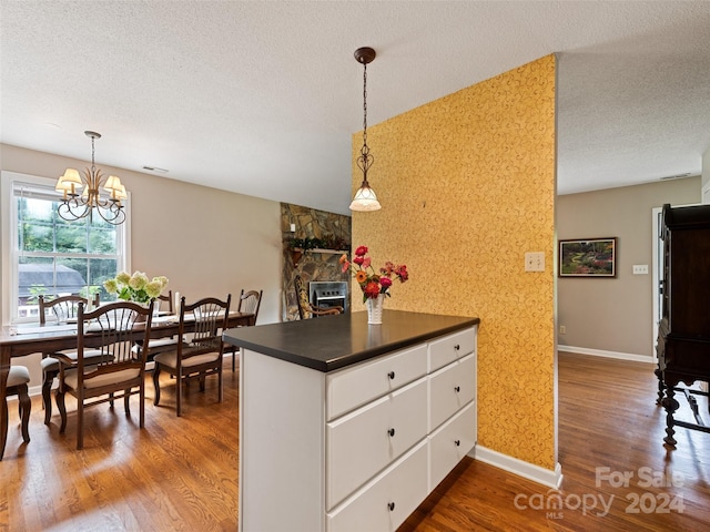 kitchen featuring a textured ceiling, wallpapered walls, dark countertops, and dark wood-style floors