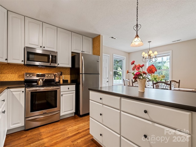 kitchen with a notable chandelier, light wood-style flooring, dark countertops, visible vents, and stainless steel appliances