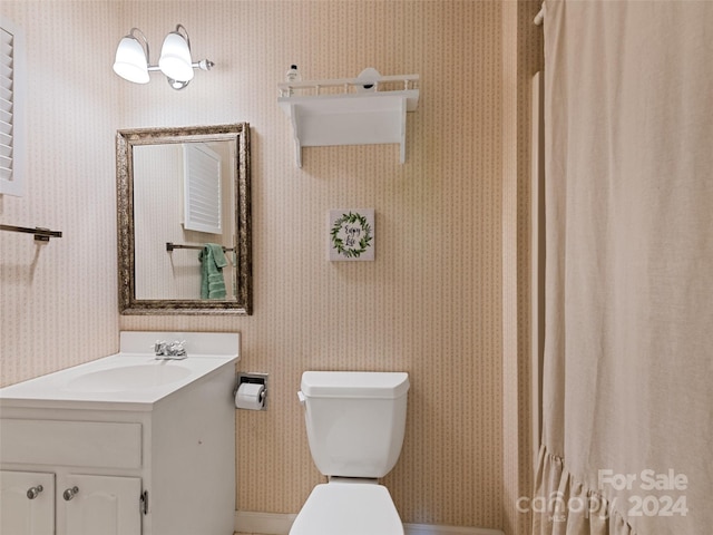 bathroom featuring toilet, vanity, a shower with curtain, and wallpapered walls