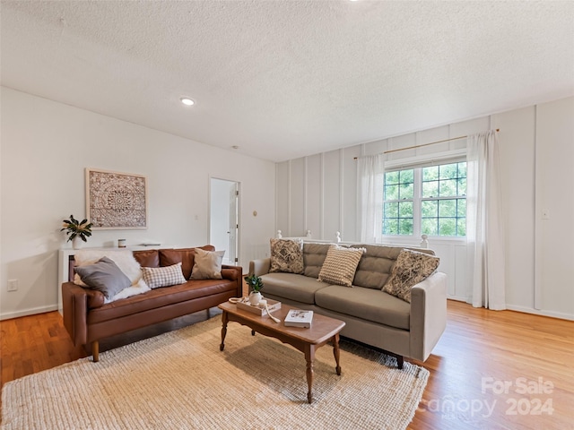 living area with light wood-style floors, recessed lighting, baseboards, and a textured ceiling