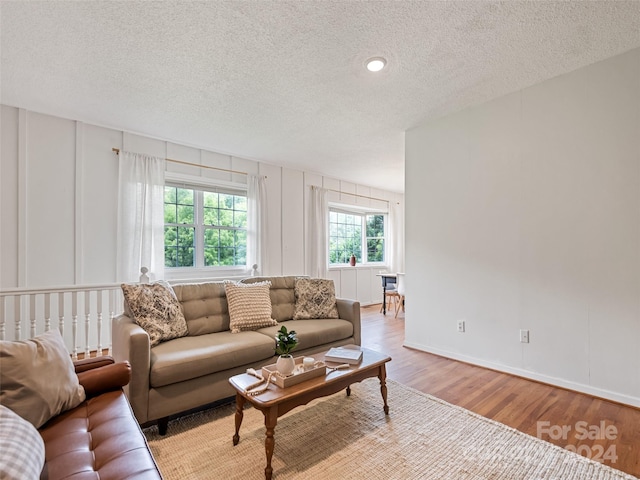 living area featuring a textured ceiling, baseboards, and wood finished floors