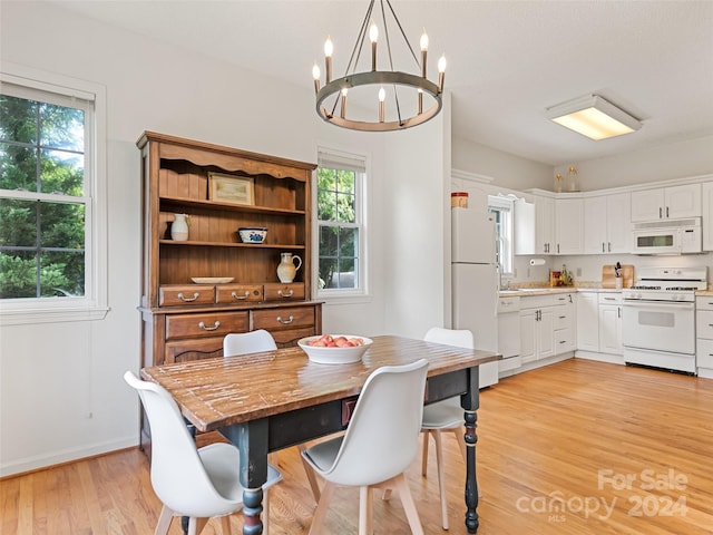 dining room with light wood-style flooring, a chandelier, and baseboards