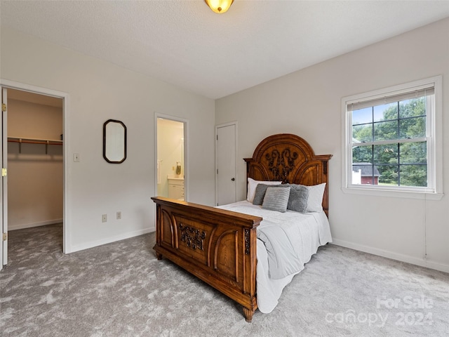 bedroom with ensuite bathroom, a closet, carpet floors, a walk in closet, and baseboards