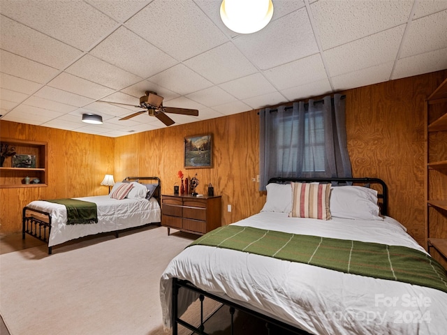 carpeted bedroom with wood walls and ceiling fan