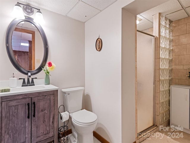 full bathroom with toilet, a shower stall, a drop ceiling, and vanity
