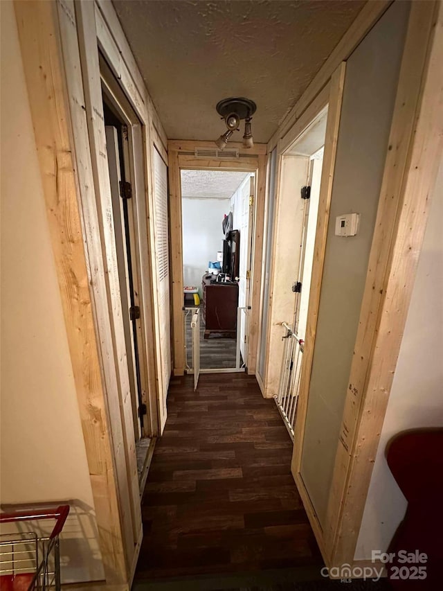 corridor with a textured ceiling and dark hardwood / wood-style flooring