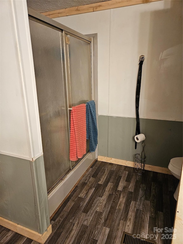 bathroom featuring toilet, a shower with door, and hardwood / wood-style flooring