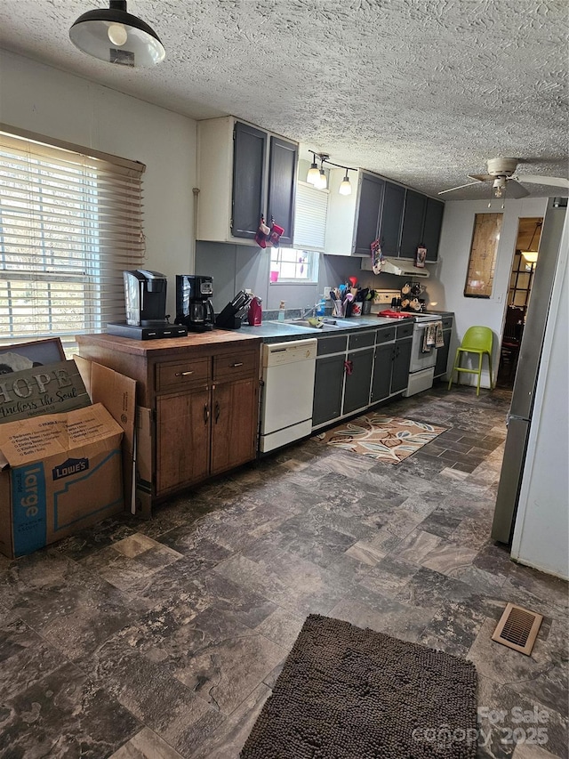 kitchen featuring ceiling fan, sink, white appliances, and a textured ceiling