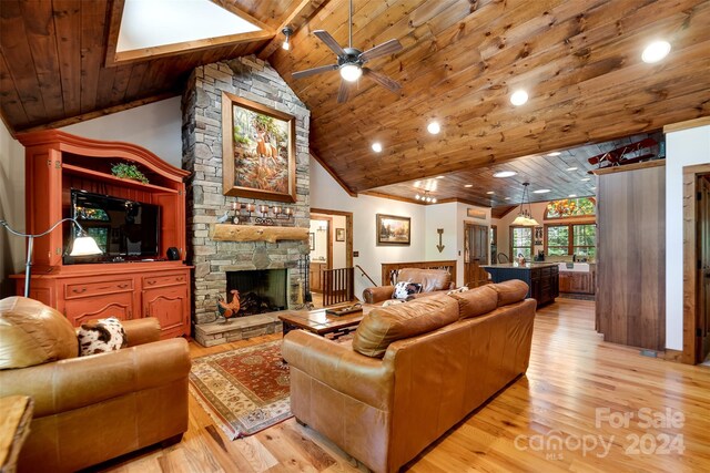 living room with light hardwood / wood-style flooring, ceiling fan, a stone fireplace, wood ceiling, and beam ceiling