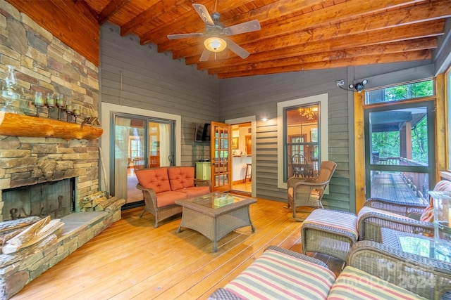 living room with a fireplace, wooden ceiling, light hardwood / wood-style floors, ceiling fan, and vaulted ceiling with beams