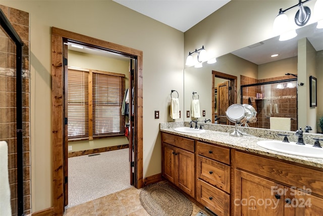 bathroom featuring double vanity, a stall shower, a sink, and baseboards