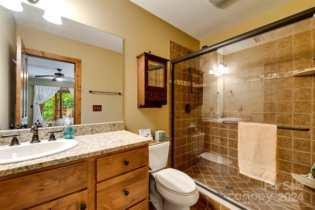 bathroom with ceiling fan, toilet, a shower with door, and vanity