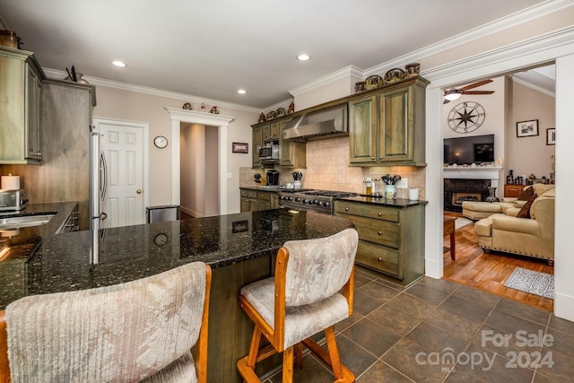 kitchen with kitchen peninsula, crown molding, a kitchen bar, dark hardwood / wood-style flooring, and ceiling fan