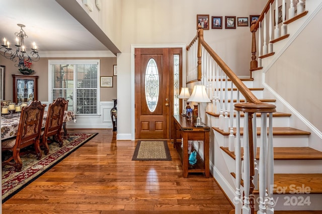 foyer with crown molding, a notable chandelier, and dark hardwood / wood-style floors