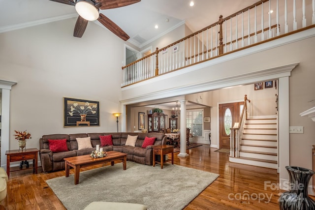 living room with a towering ceiling, dark hardwood / wood-style floors, ornate columns, and ceiling fan