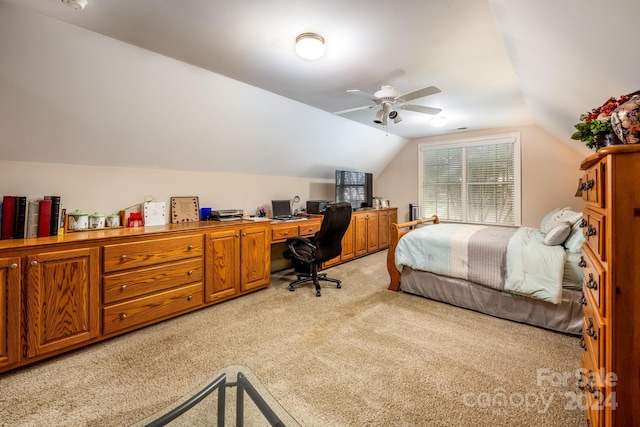 bedroom featuring built in desk, vaulted ceiling, light colored carpet, and ceiling fan