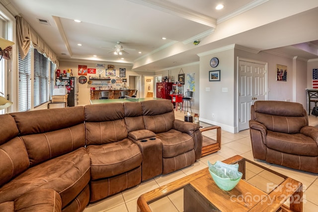 tiled living room with ornamental molding, a tray ceiling, and ceiling fan