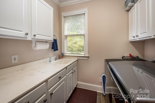 washroom featuring dark tile patterned flooring, sink, crown molding, separate washer and dryer, and cabinets