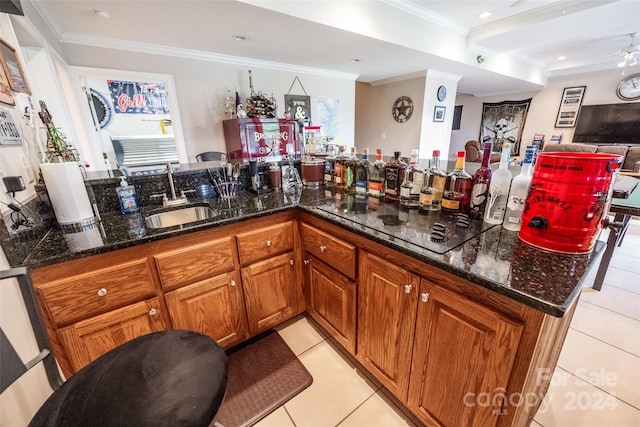 kitchen featuring crown molding, dark stone countertops, sink, and light tile patterned floors