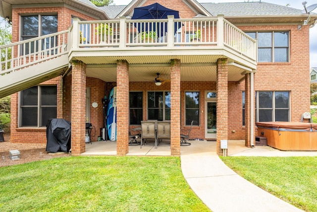 back of property with a hot tub, a patio, and a lawn