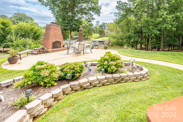 view of yard with an outdoor brick fireplace and a patio area