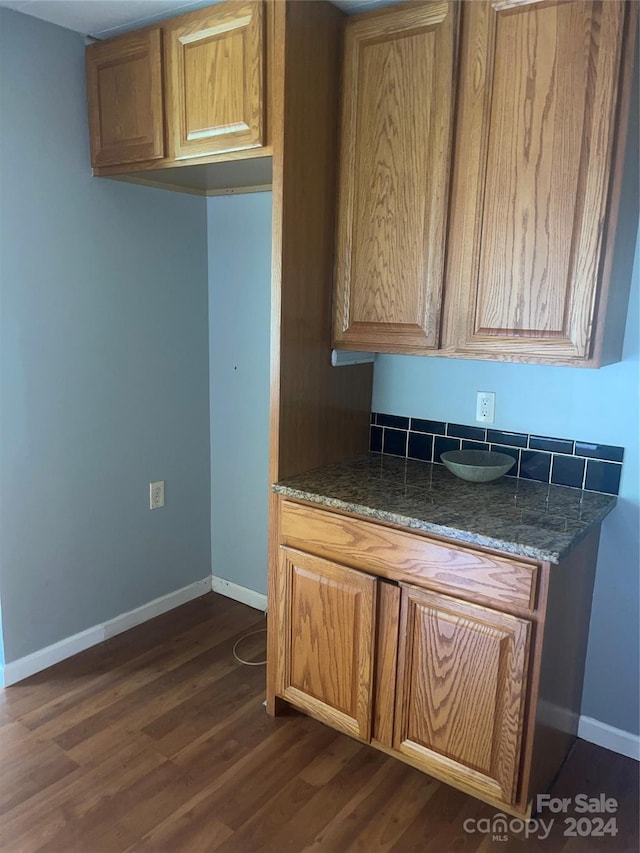 kitchen with dark stone counters and dark hardwood / wood-style flooring