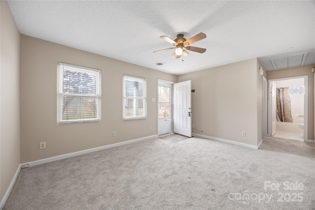 spare room with light carpet, attic access, baseboards, and a textured ceiling