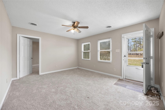 interior space with light carpet, a textured ceiling, visible vents, and baseboards