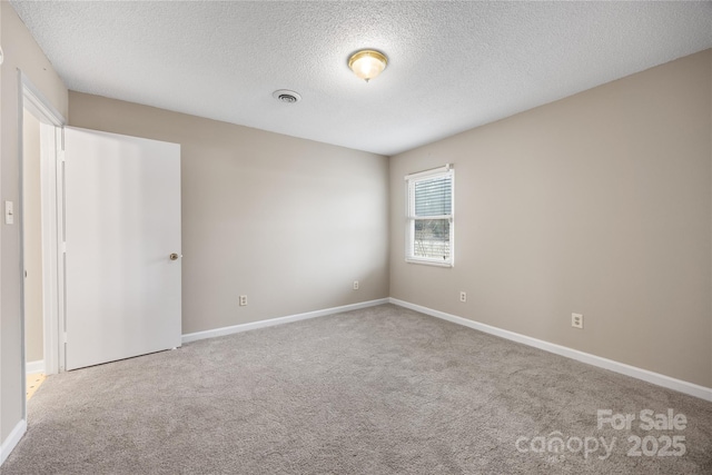 empty room featuring light carpet, a textured ceiling, visible vents, and baseboards