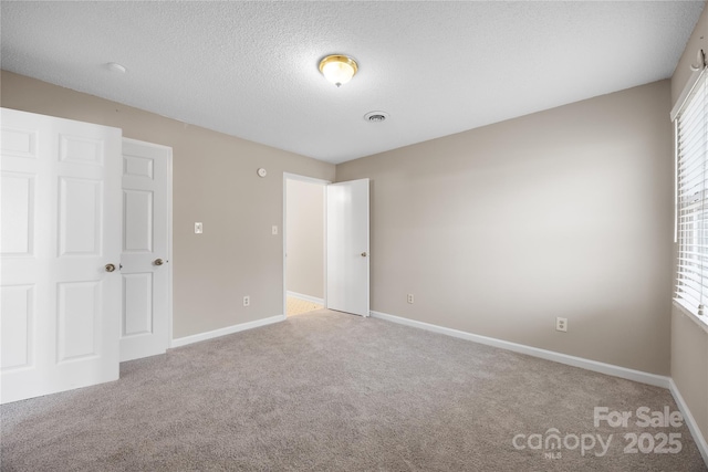 interior space with carpet floors, visible vents, a textured ceiling, and baseboards