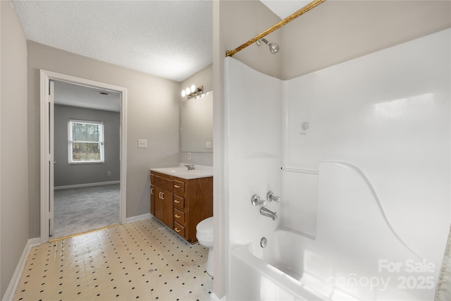 bathroom with a textured ceiling, toilet, vanity, baseboards, and shower / washtub combination