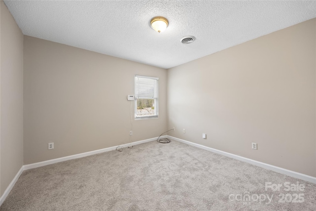 carpeted spare room with baseboards, visible vents, and a textured ceiling