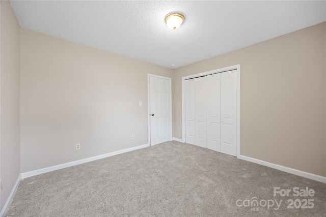 unfurnished bedroom with carpet, a textured ceiling, baseboards, and a closet