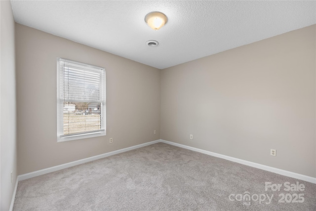 empty room with light carpet, baseboards, visible vents, and a textured ceiling