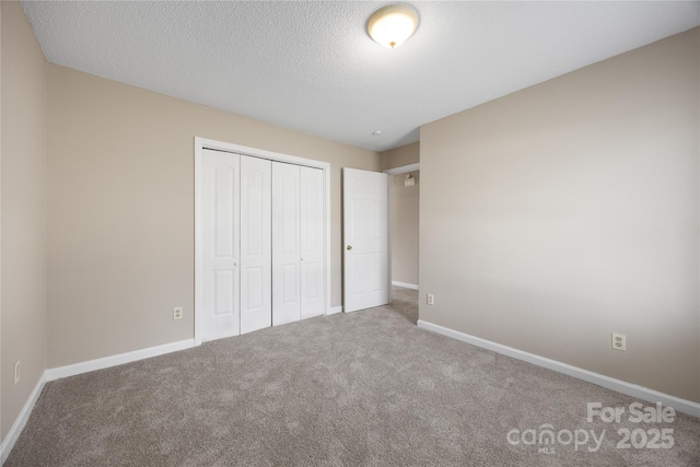 unfurnished bedroom featuring a closet, carpet flooring, a textured ceiling, and baseboards