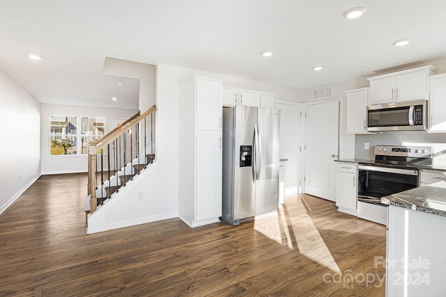 kitchen with dark wood-type flooring, dark stone counters, decorative backsplash, white cabinetry, and stainless steel appliances