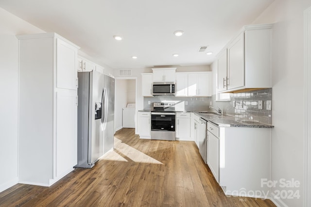 kitchen with light stone counters, stainless steel appliances, sink, white cabinets, and hardwood / wood-style floors