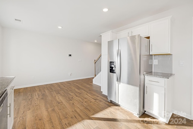 kitchen with white cabinetry, stainless steel appliances, light stone counters, and light hardwood / wood-style floors