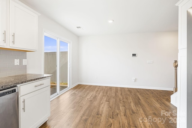 kitchen featuring dishwasher, light hardwood / wood-style flooring, white cabinetry, and dark stone counters