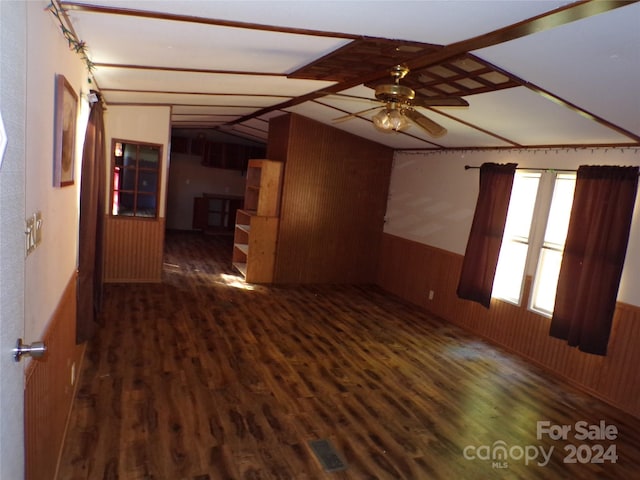 spare room featuring visible vents, wainscoting, vaulted ceiling, wood walls, and wood finished floors