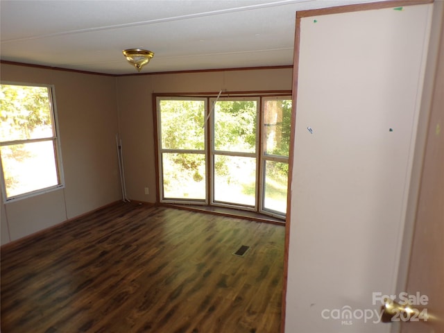 spare room with visible vents, dark wood-style flooring, and ornamental molding