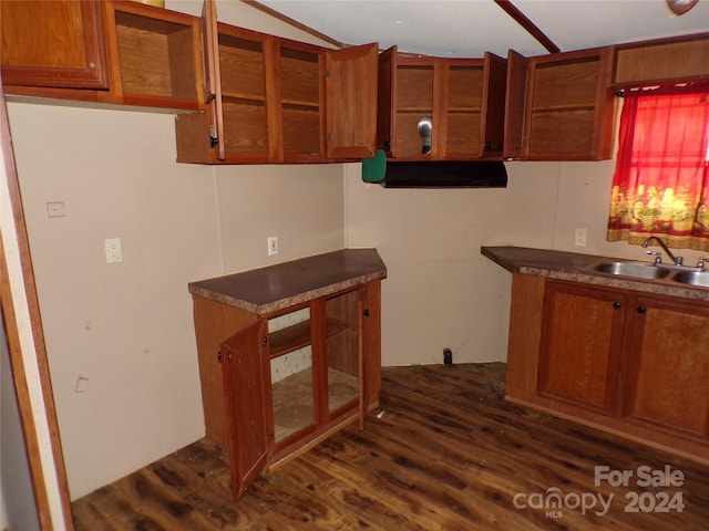 kitchen with a sink, dark wood-style floors, open shelves, brown cabinetry, and glass insert cabinets