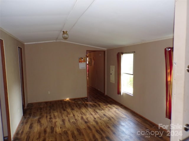 empty room with vaulted ceiling, ornamental molding, and wood finished floors