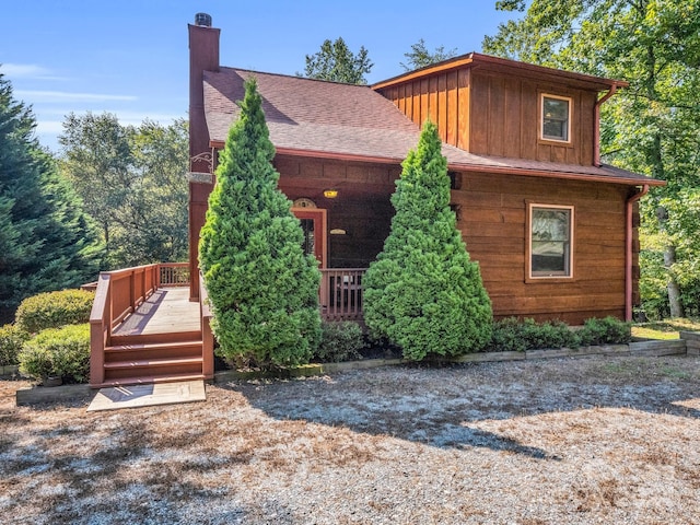 view of front facade featuring a shingled roof, a chimney, and board and batten siding