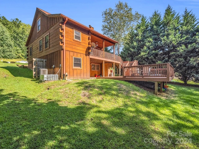 rear view of house featuring a deck, a yard, a chimney, and board and batten siding