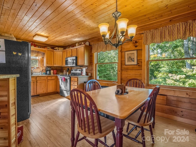 dining room featuring wooden walls, light wood finished floors, wooden ceiling, and a healthy amount of sunlight